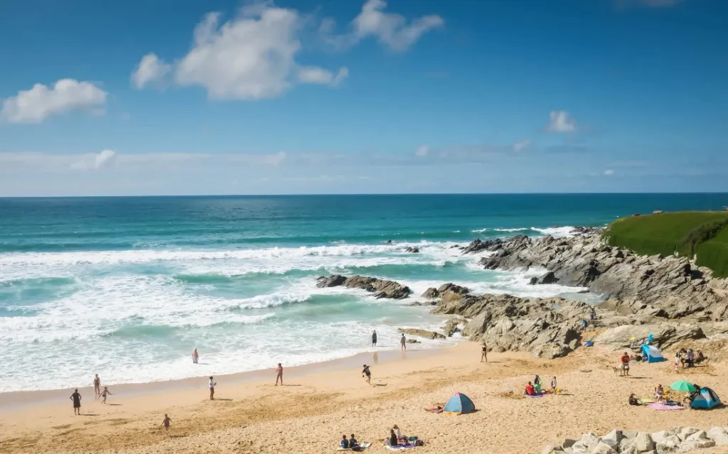 Surfers and beachgoers on a sandy cove in Cornwall
