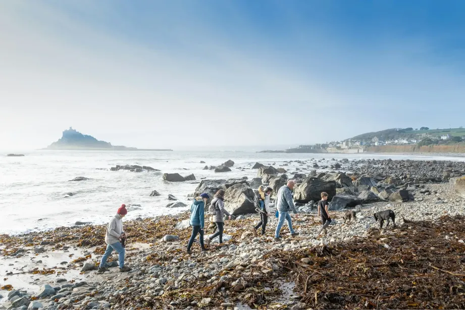 Family walking a dog along a rocky Cornish beach
